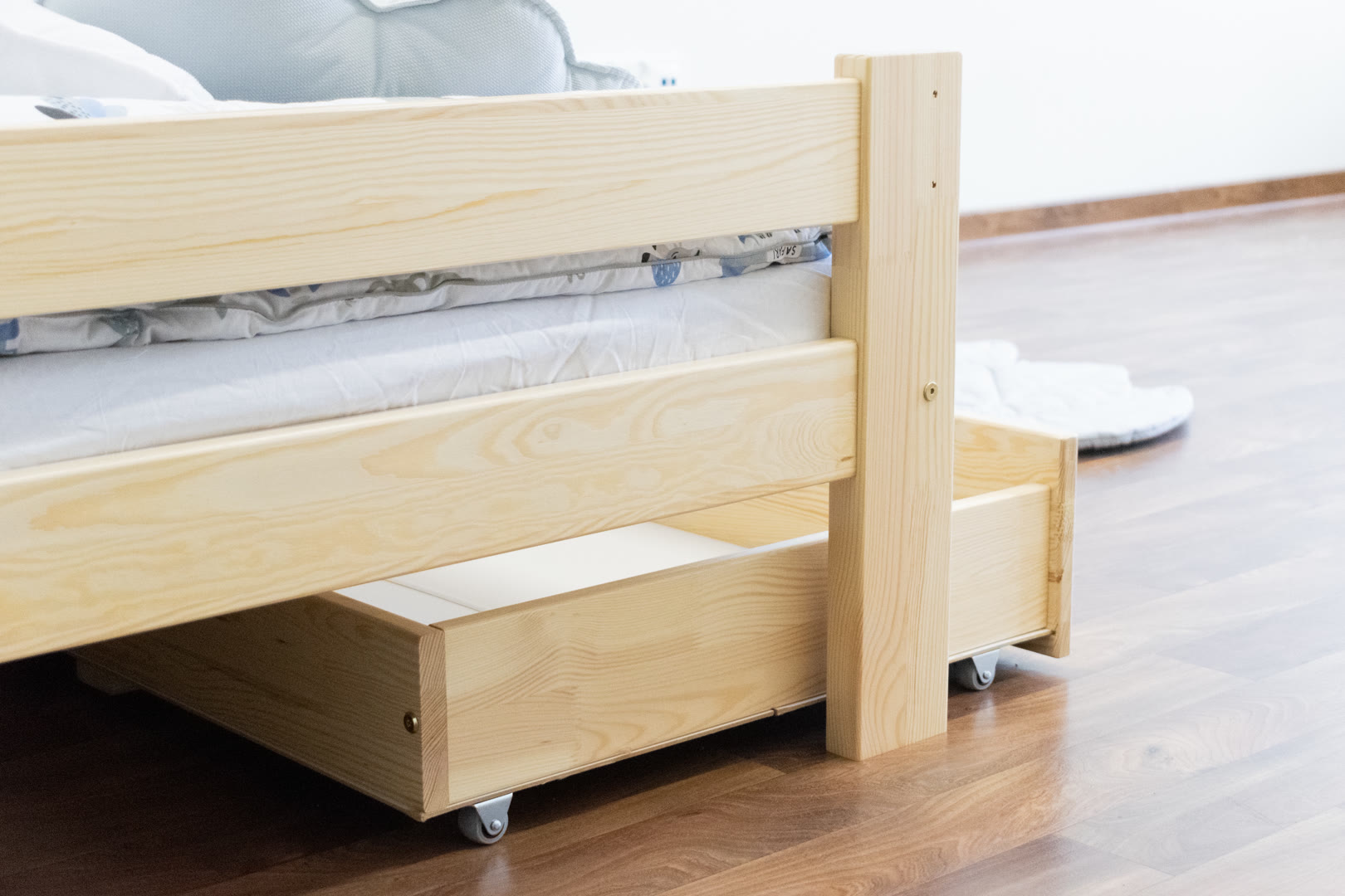 łóżko dziecięce z drewna sosnowego z dużą szufladą pod łóżkiem model Pawełek Max w małym pokoju